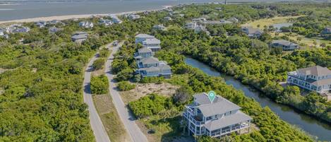 An aerial view of a residential area with houses, a river, and a beach.