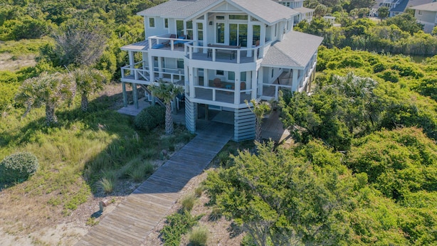 A multi-story beachfront house with a wooden deck and multiple balconies. - Oceanview. Steps to South Beach • Stunning Sunset Views • Golf Carts Included • (Bald Head Island)