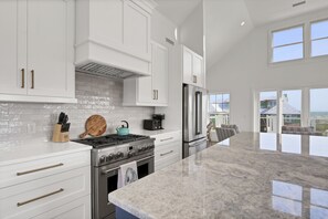 A modern kitchen with white cabinetry, stainless steel appliances, and a large island.