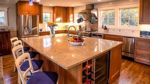 Eine moderne Küche mit Granit Arbeitsplatten, Edelstahlgeräten und Holzschränken.