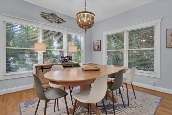 A dining room with a wooden table, six chairs, and two lamps.