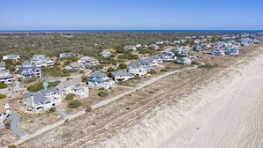Vista aérea de una zona residencial costera con casas a lo largo de una playa arenosa.