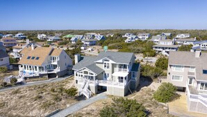 Zona residencial costera con casas de varios pisos, balcones y un camino de acceso a la playa.