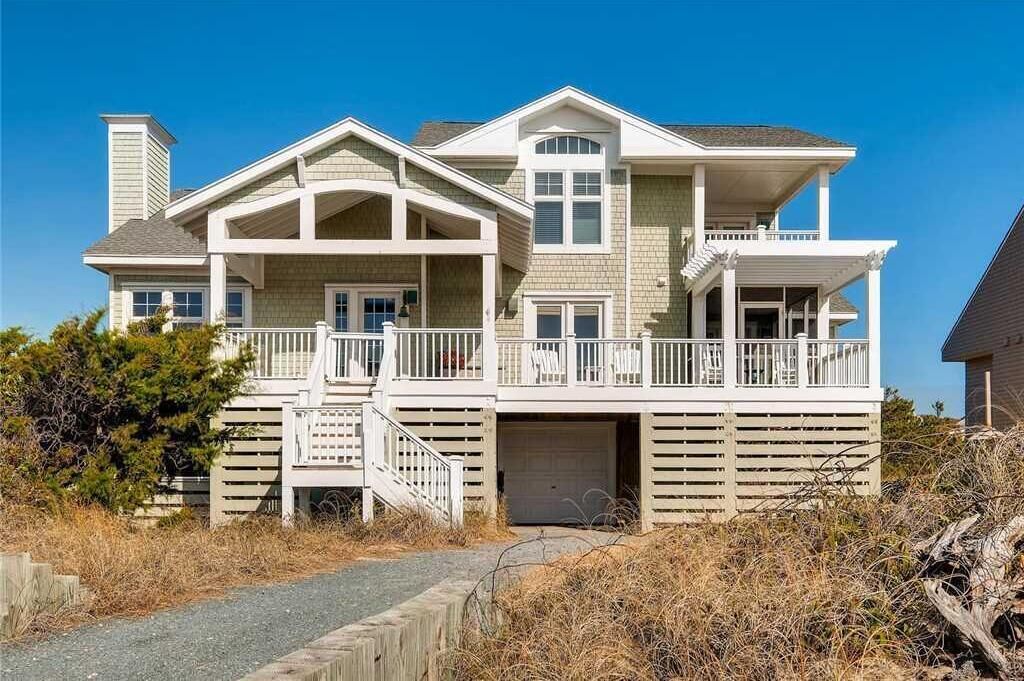 A two-story house with a covered front porch, a garage, and a small deck.