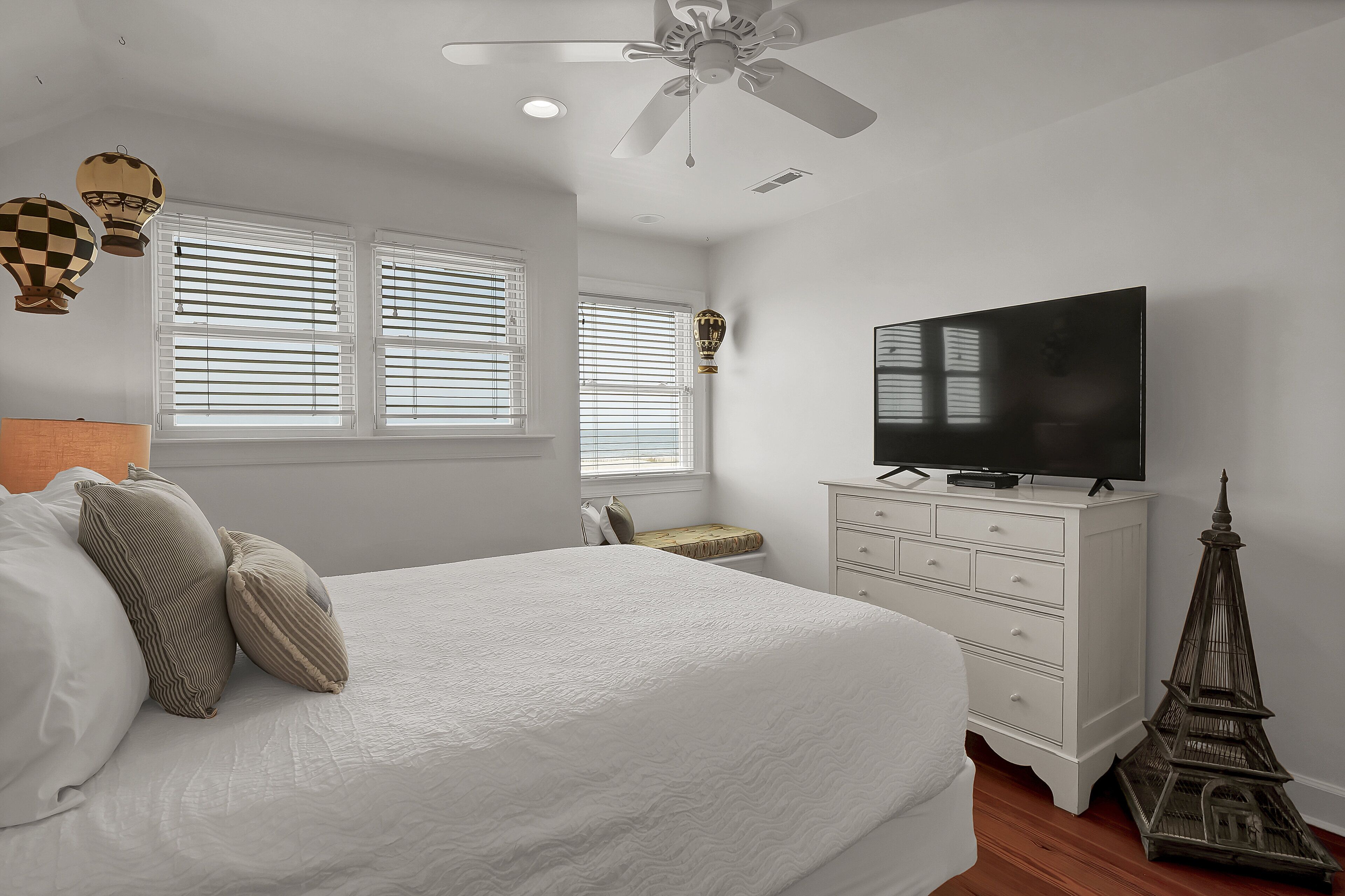 A bedroom with a large bed, a television, a dresser, and a decorative Eiffel Tower.