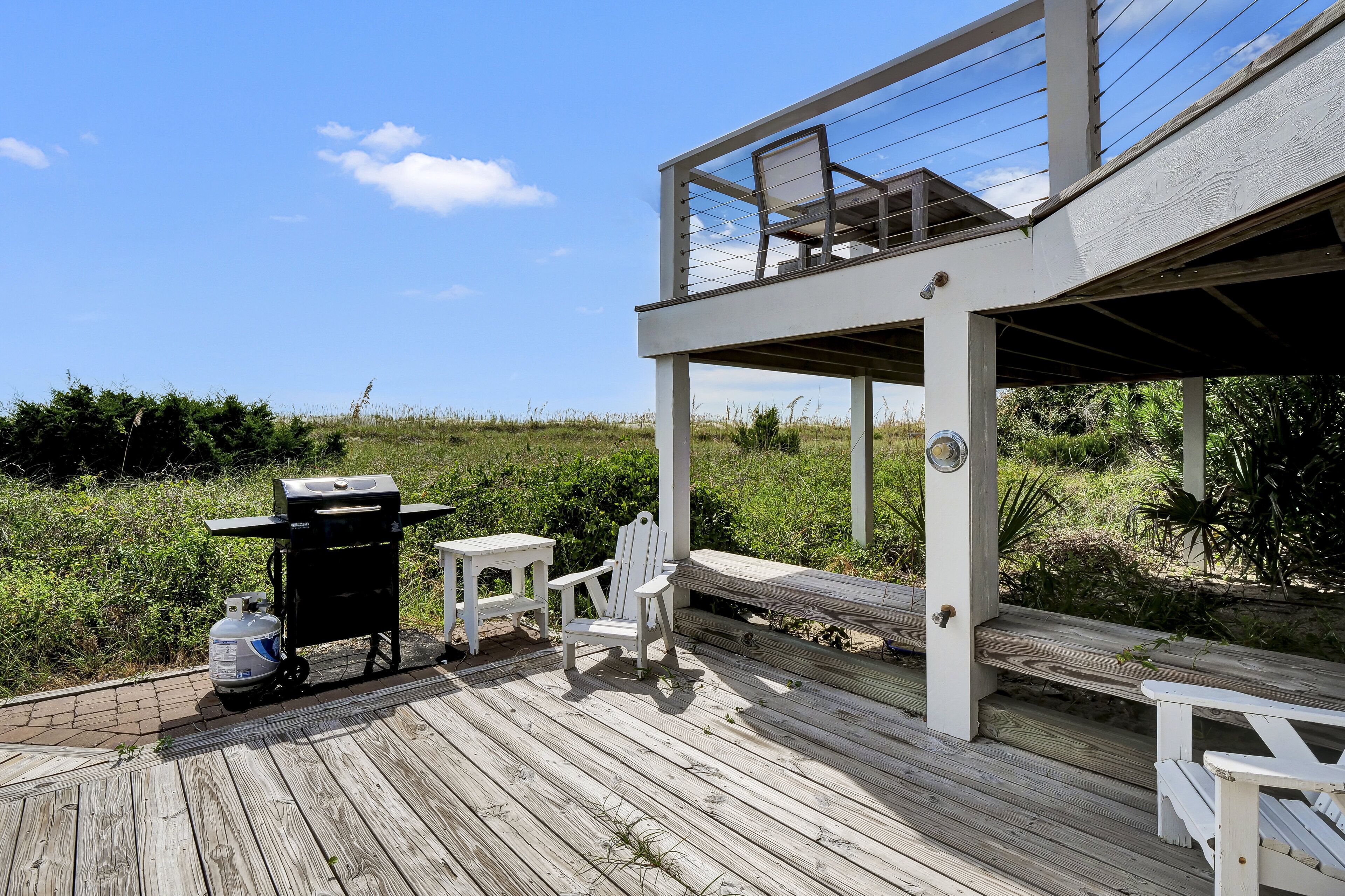 Une terrasse en bois avec un barbecue, des chaises et une table.