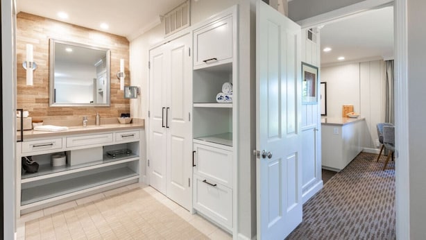 Une salle de bain moderne avec un grand miroir, des meubles blancs et un meuble-lavabo avec un évier.