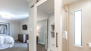 Une chambre d’hôtel comprenant un lit, une télévision, une armoire et une salle de bain avec douche et fenêtre.