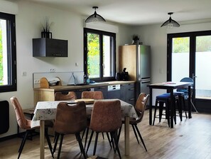 Una cocina moderna con comedor, ventanas amplias y vistas a zonas verdes.