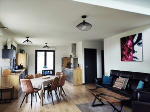 Un espacio habitable moderno con comedor, cocina y un sofá de cuero negro.
