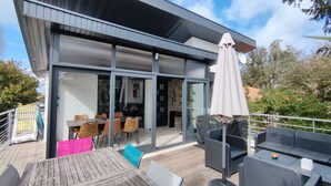 A modern building with a patio area featuring outdoor seating and a covered umbrella. - Beautiful apartment for up to 6 people, south-facing terrace, beach on foot! (La Tremblade)