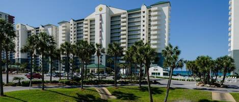 A hotel with multiple white buildings, palm trees, and a clear blue sky.