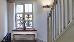 A staircase with a handrail, a radiator, a wooden bench, and a patterned rug.