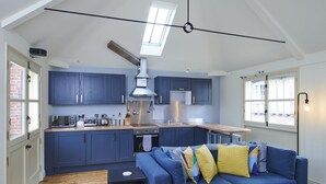A compact kitchen with dark blue cabinets, a wooden countertop, and a skylight above.