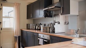 A modern kitchen with dark cabinets, stainless steel appliances, and a wooden countertop.