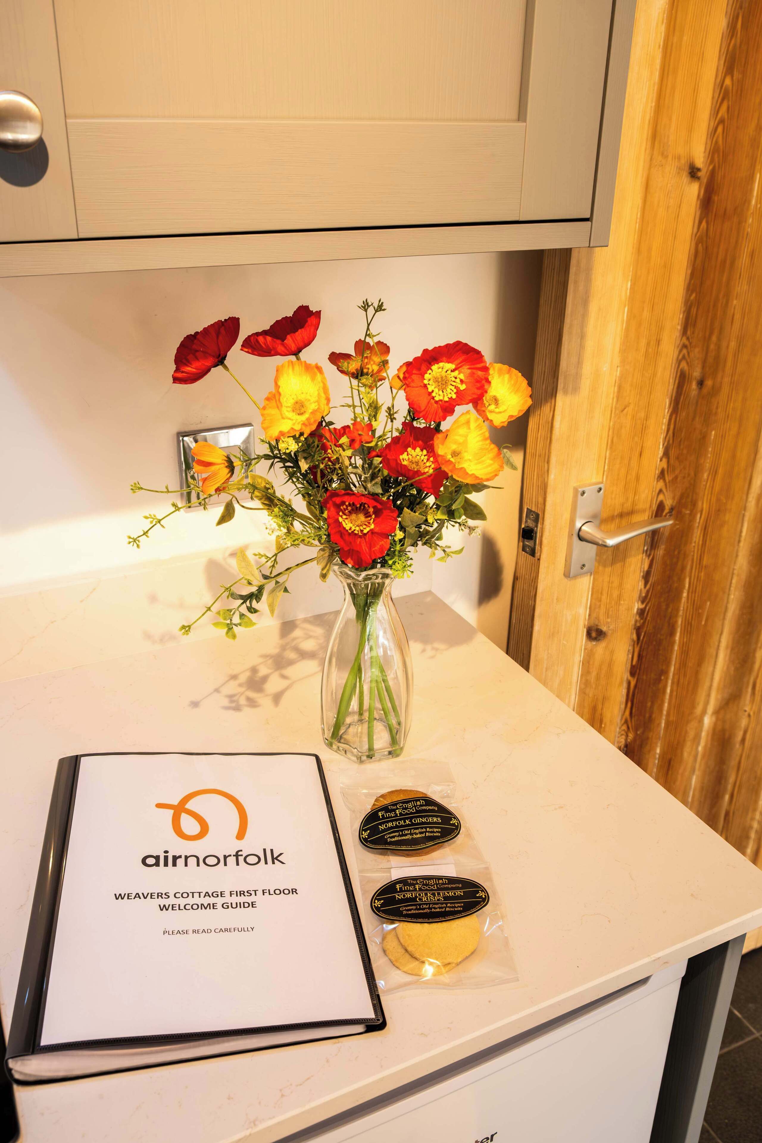 A welcome guide, a vase with flowers, and a door.