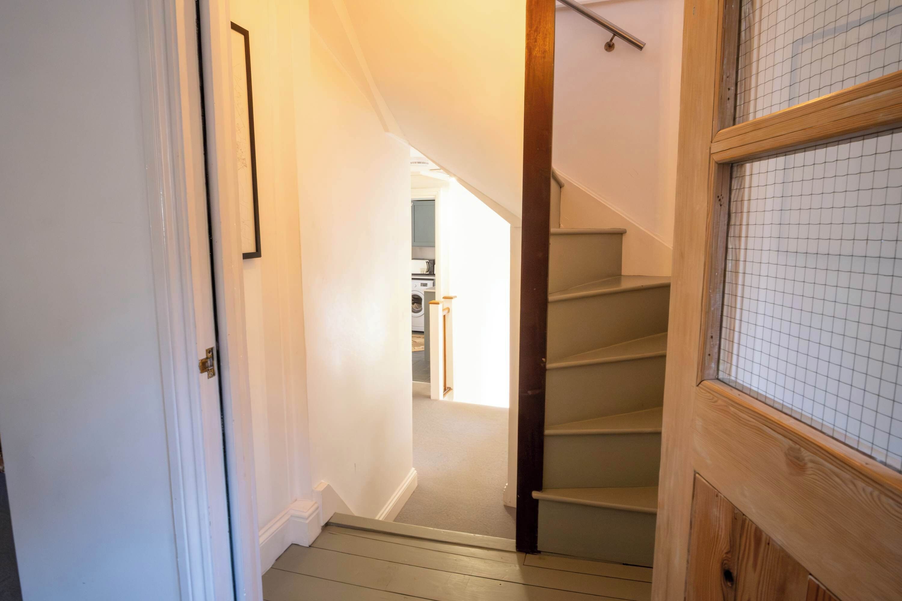 A staircase leading to a second-floor area with a kitchen visible in the background.