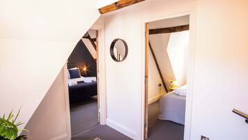 Une pièce comprenant un lit, une table de chevet, un miroir et une porte donnant sur une autre pièce.