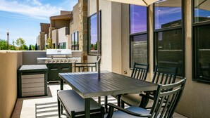 An outdoor patio area with a grill, table, and chairs.