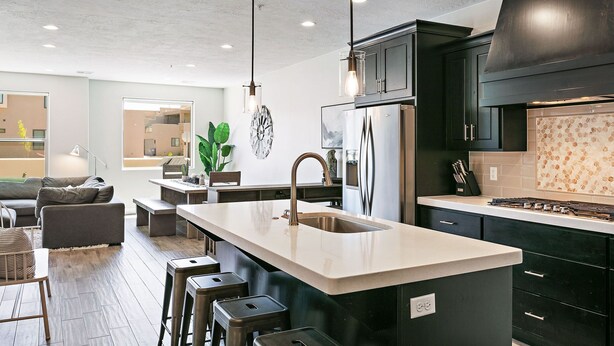 A modern kitchen with a central island, stainless steel appliances, and dark cabinetry.