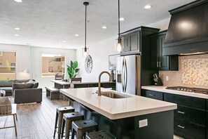Uma cozinha moderna com ilha central, eletrodomésticos de aço inoxidável e armários escuros.