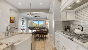 Una cocina moderna con armarios blancos, encimera de granito y estufa a gas.