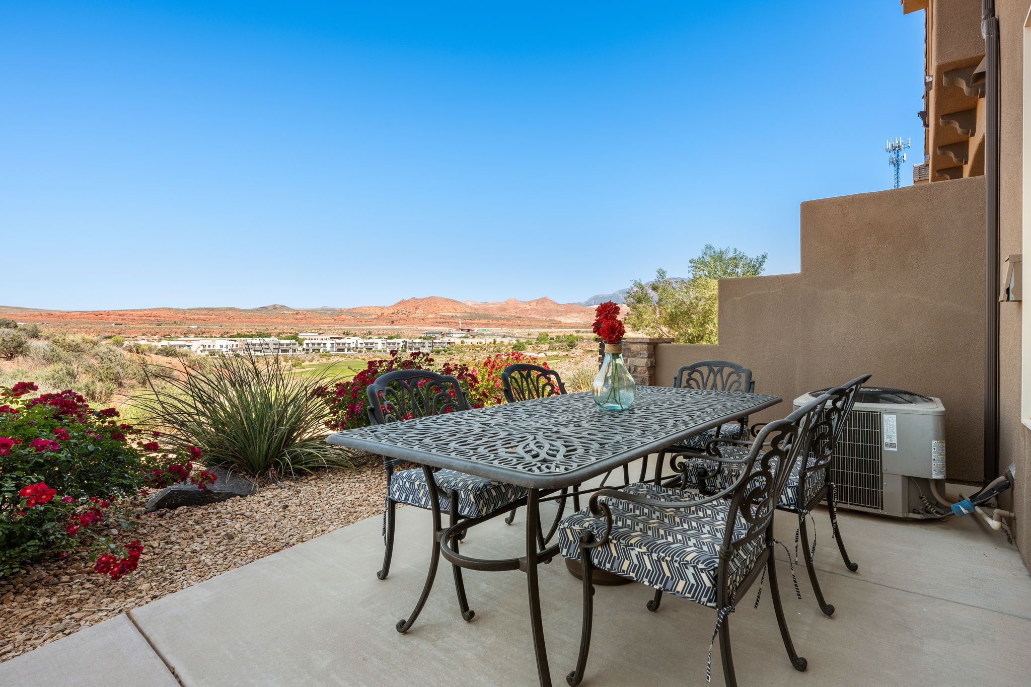 Une terrasse extérieure avec une table et des chaises, un vase décoratif et un appareil de climatisation.