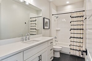 A modern bathroom with a white vanity, a large mirror, a toilet, and a shower with a black and white striped curtain. - Desert Escape- Private Hot Tub! Book with next door unit! (Washington)