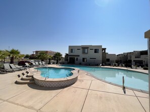 A swimming pool with lounge chairs, a hot tub, and a modern building in the background. - Desert Escape- Private Hot Tub! Book with next door unit! (Washington)