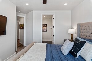 A bedroom with a bed, a nightstand, a lamp, and a door leading to another room. - Desert Escape- Private Hot Tub! Book with next door unit! (Washington)