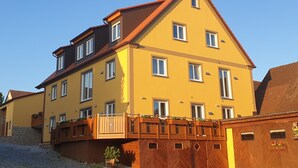 A multi-story building with a yellow facade, multiple windows, and a wooden balcony. - Vacation apartment Landglück Seegraben (Bechhofen)