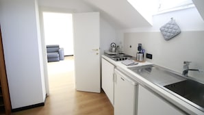 A modern kitchen with a skylight, white cabinets, and a stainless steel sink. - House Ducale (Genoa)