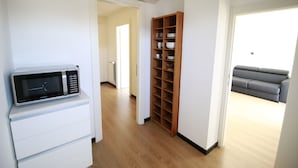 A kitchen with a microwave, a white cabinet, and a wooden shelving unit. - House Ducale (Genoa)