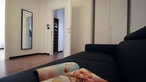A modern living room with a dark sofa, a large mirror, and a bookshelf. - House Ducale (Genoa)