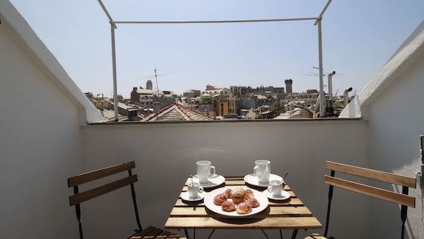 A balcony with a table set for two, a plate of pastries, and two cups. - House Ducale (Genoa)