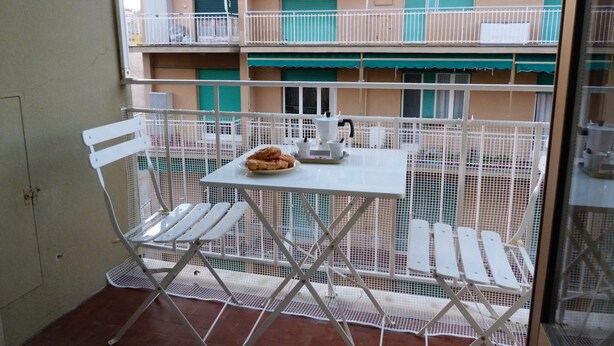 A balcony with a table and chairs, a small table with a teapot and cups, and a plate of pastries. - House Bia (Genoa)