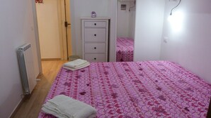 A bedroom with a bed, a dresser, a radiator, and a door. - House Bia (Genoa)