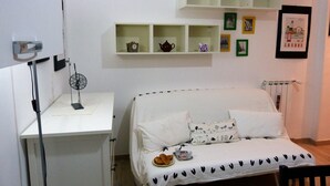 A neatly arranged bedroom with a bed, bedside table, and shelves with framed pictures. - House Bia (Genoa)