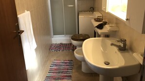 A bathroom with a shower, toilet, sink, and a small window. - House Orsa Maggiore (Bordighera)