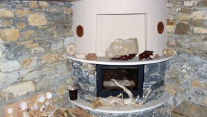 A stone fireplace with decorative shells and a basket of firewood. - House Limone (Recco)