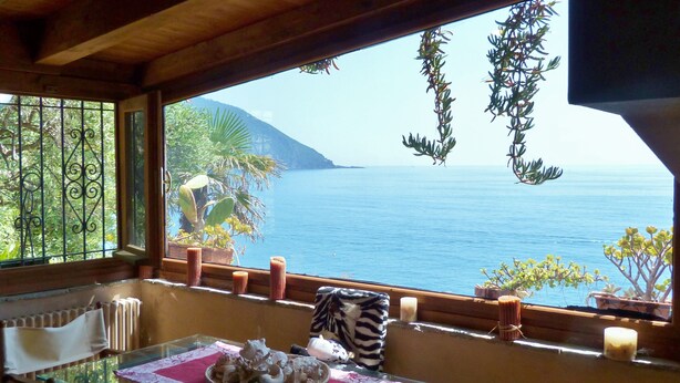A dining area with a glass table, chairs, and a view of the sea. - House Limone (Recco)