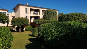A multi-story residential building with a flat roof, surrounded by well-maintained hedges and a manicured lawn. - Il Quadrifoglio in Pineta (Arenzano)