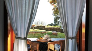 A view through sheer curtains of an outdoor dining area with wicker furniture and a table set with a teapot and cups. - Villa Limoni (Arenzano)