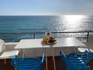 Une table avec un assortiment de fruits sur un balcon donnant sur la mer.