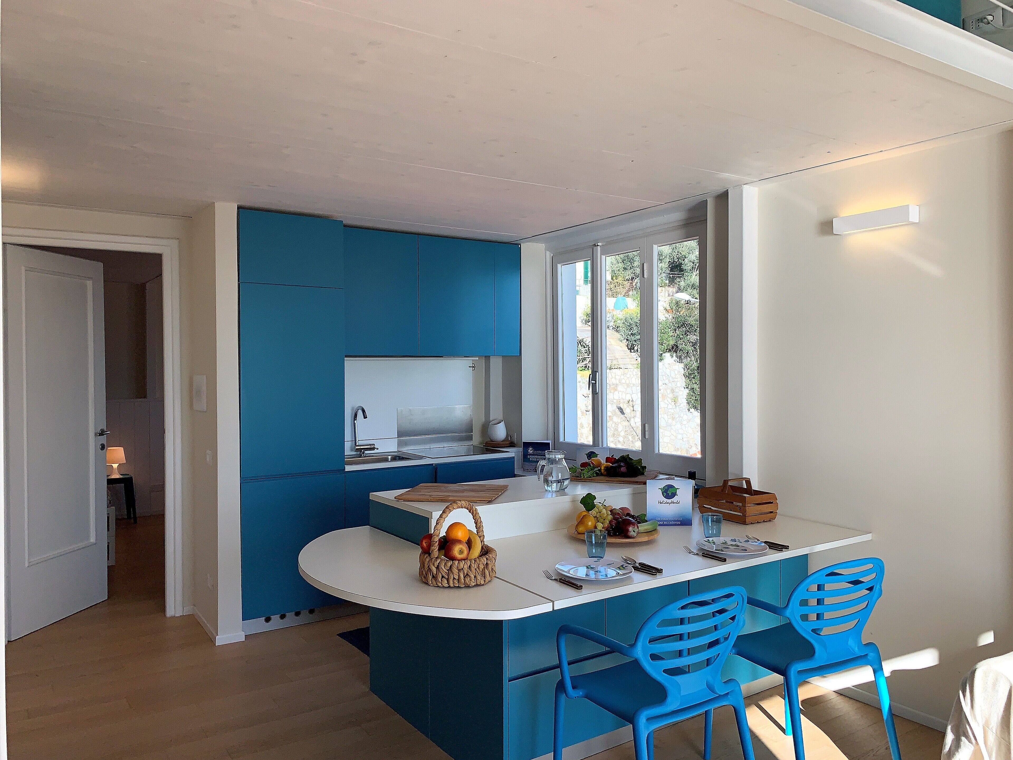 Eine moderne Küche mit blauen Schränken, einer weißen Arbeitsplatte und zwei blauen Stühlen.
