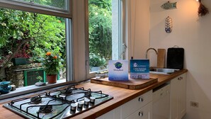 Uma cozinha com fogão a gás, pia e janela com vista para um jardim.
