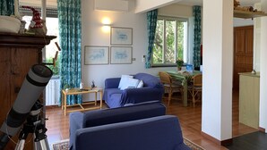 Uma sala de estar aconchegante com um sofá, uma mesa de jantar e um telescópio.