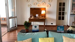 A hotel reception area with a wooden desk, a lamp, a potted plant, and a sign indicating a holiday world. - House Mediterraneo (Moneglia)