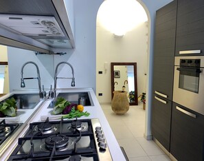A modern kitchen with a gas stove, stainless steel sink, and dark cabinetry. - House Sarzano (Genoa)
