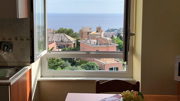 A kitchen with a window overlooking a cityscape and the sea. - House Blue Sky (Genoa)